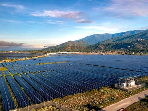 Aerial view of a large solar panel farm set against a mountainous backdrop, representative of the mountainous terrain where Bhutan's Sephu Solar Power Project is located.