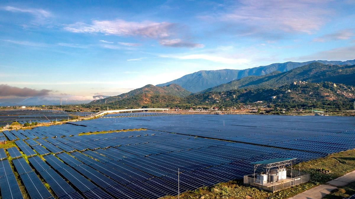 Aerial view of a large solar panel farm set against a mountainous backdrop, representative of the mountainous terrain where Bhutan's Sephu Solar Power Project is located.
