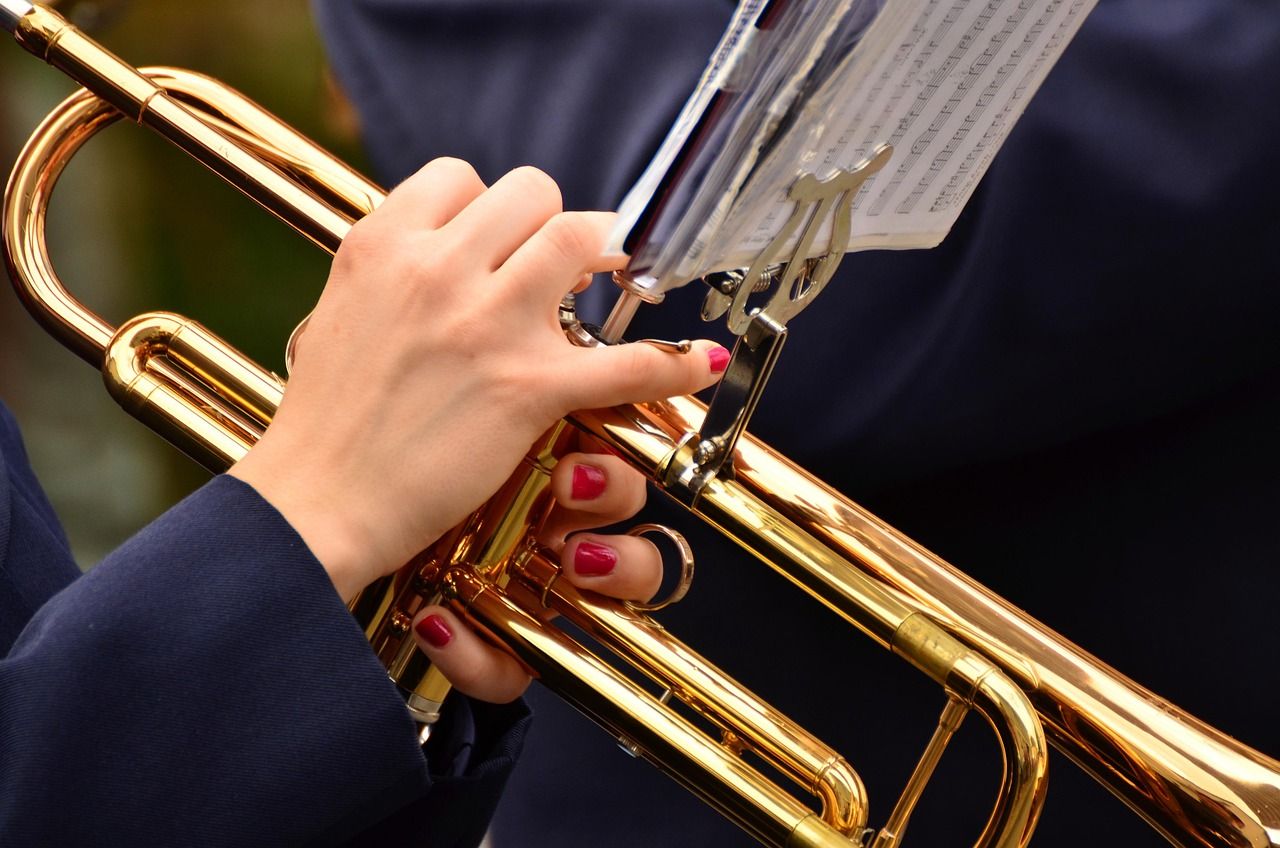 Close-up of hands holding a brass trumpet in front of sheet music