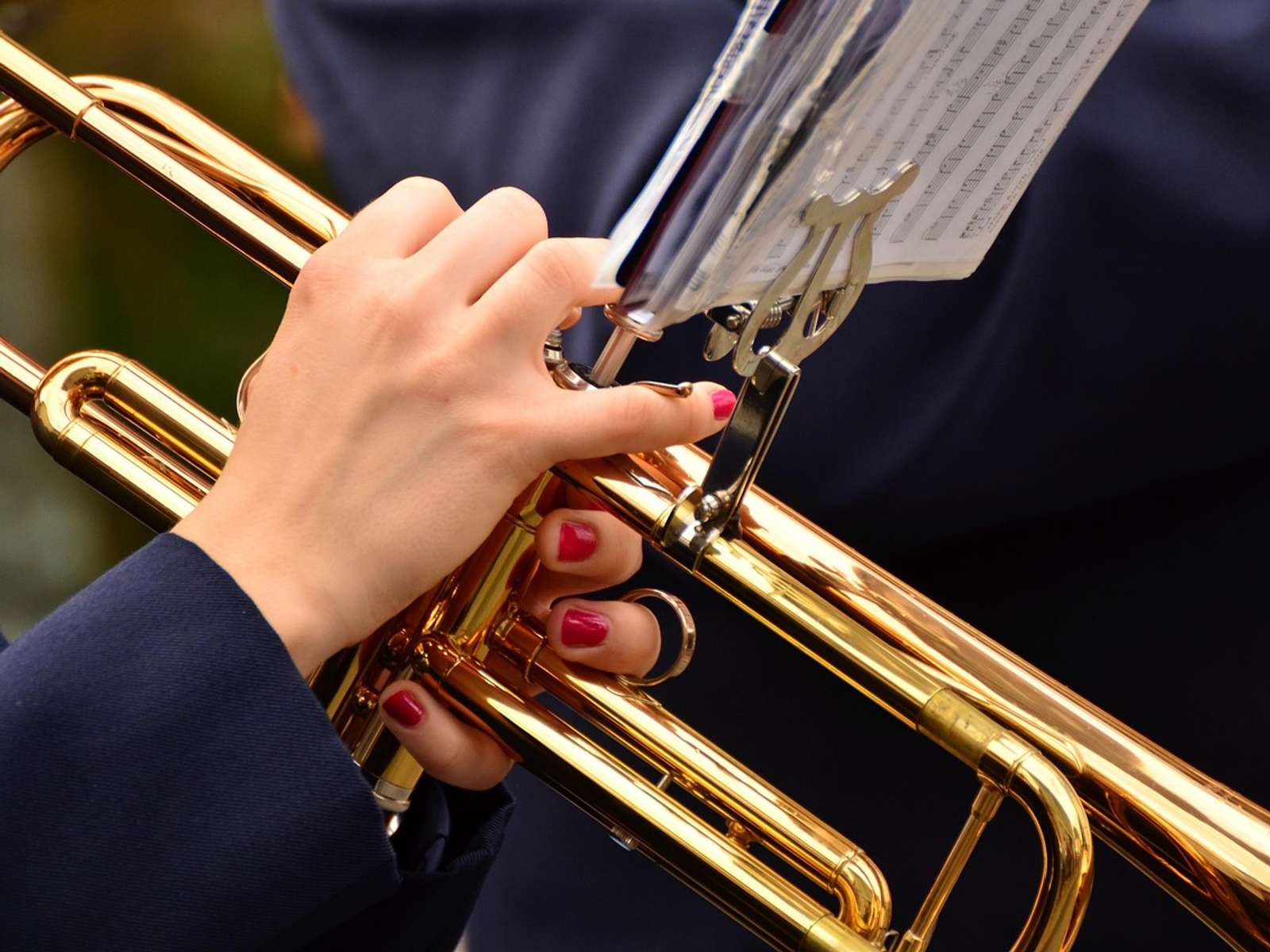 Close-up of hands holding a brass trumpet in front of sheet music