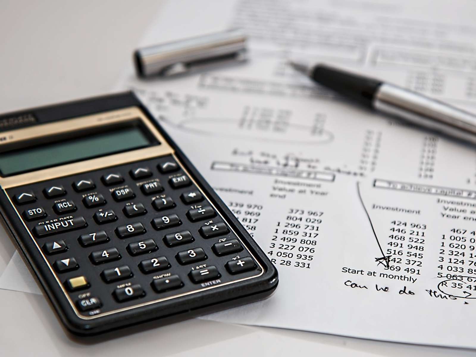 Calculator and pen on a desk with financial paperwork