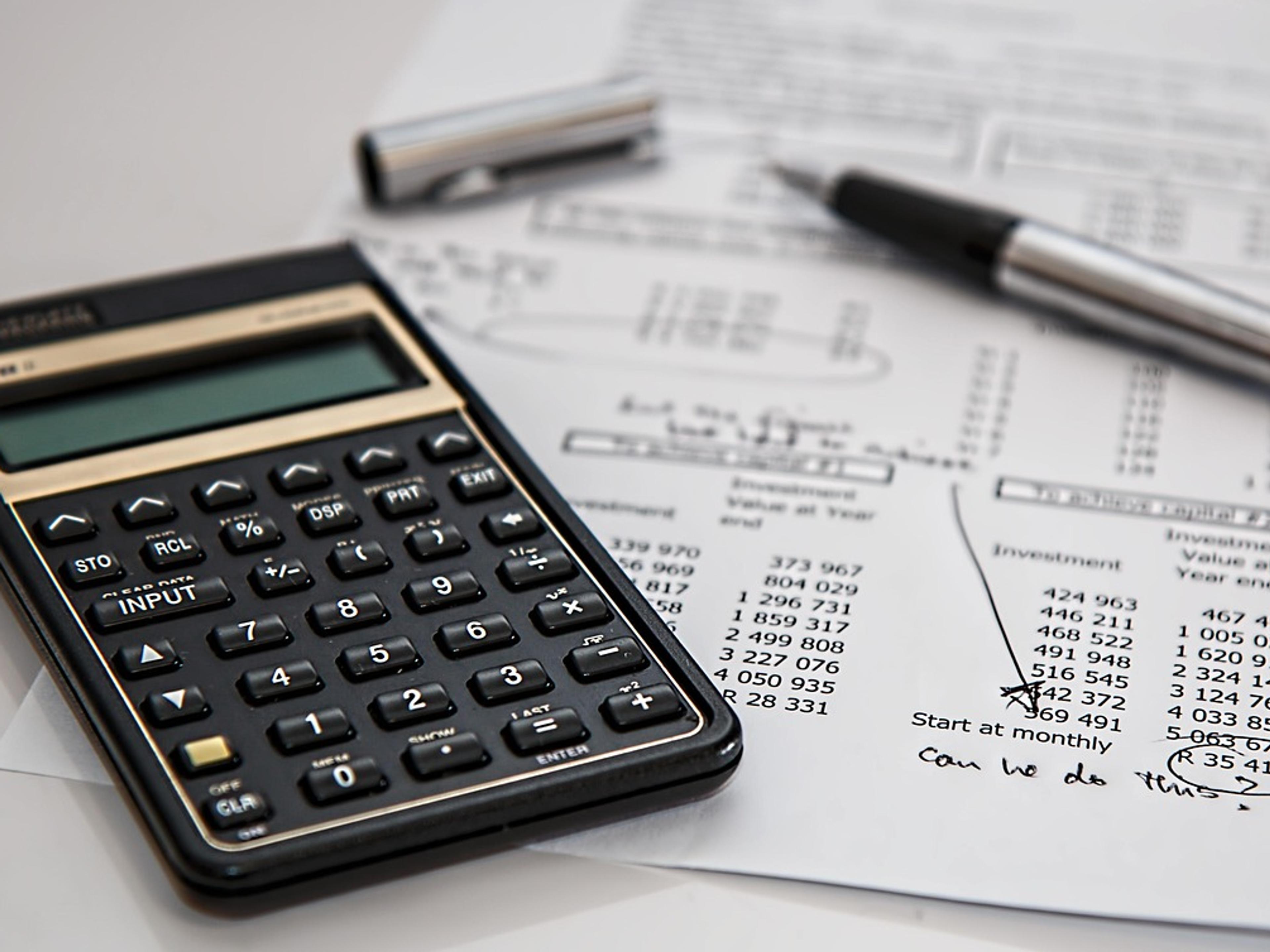 Calculator and pen on a desk with financial paperwork