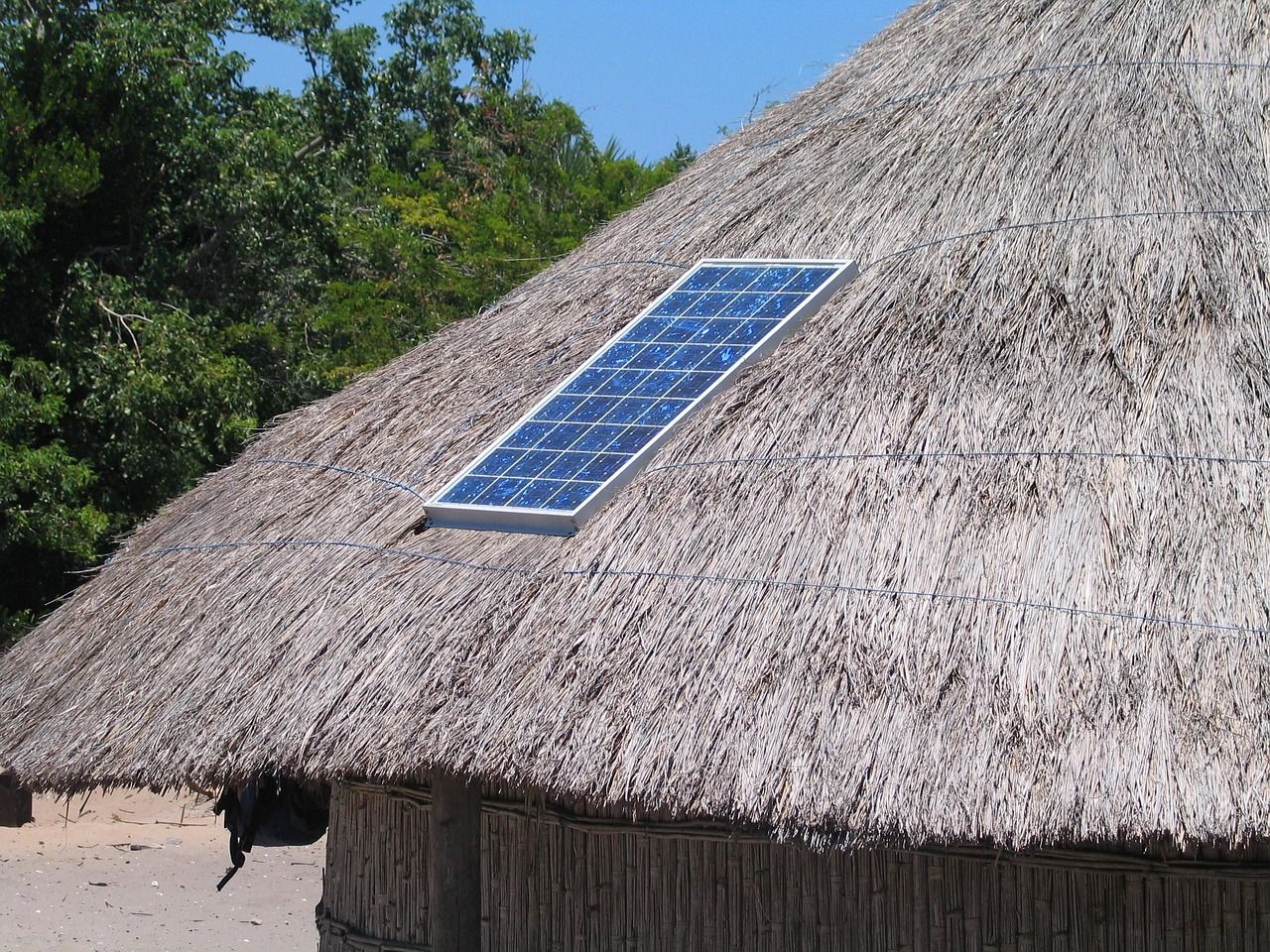 A solar panel on the thatched roof of a hut