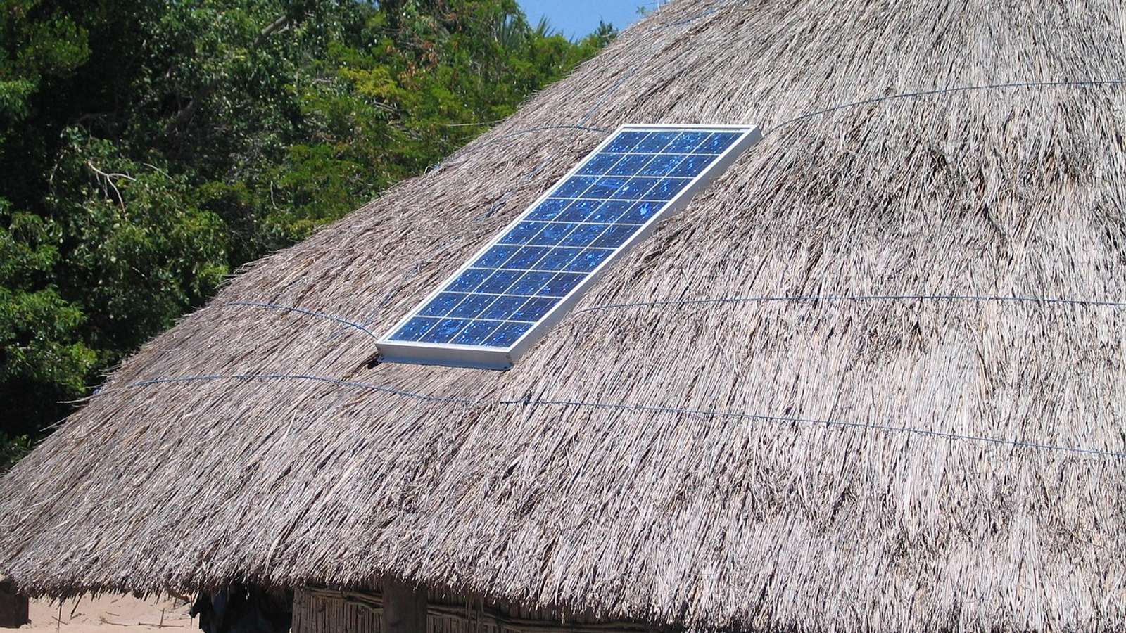 A solar panel on the thatched roof of a hut