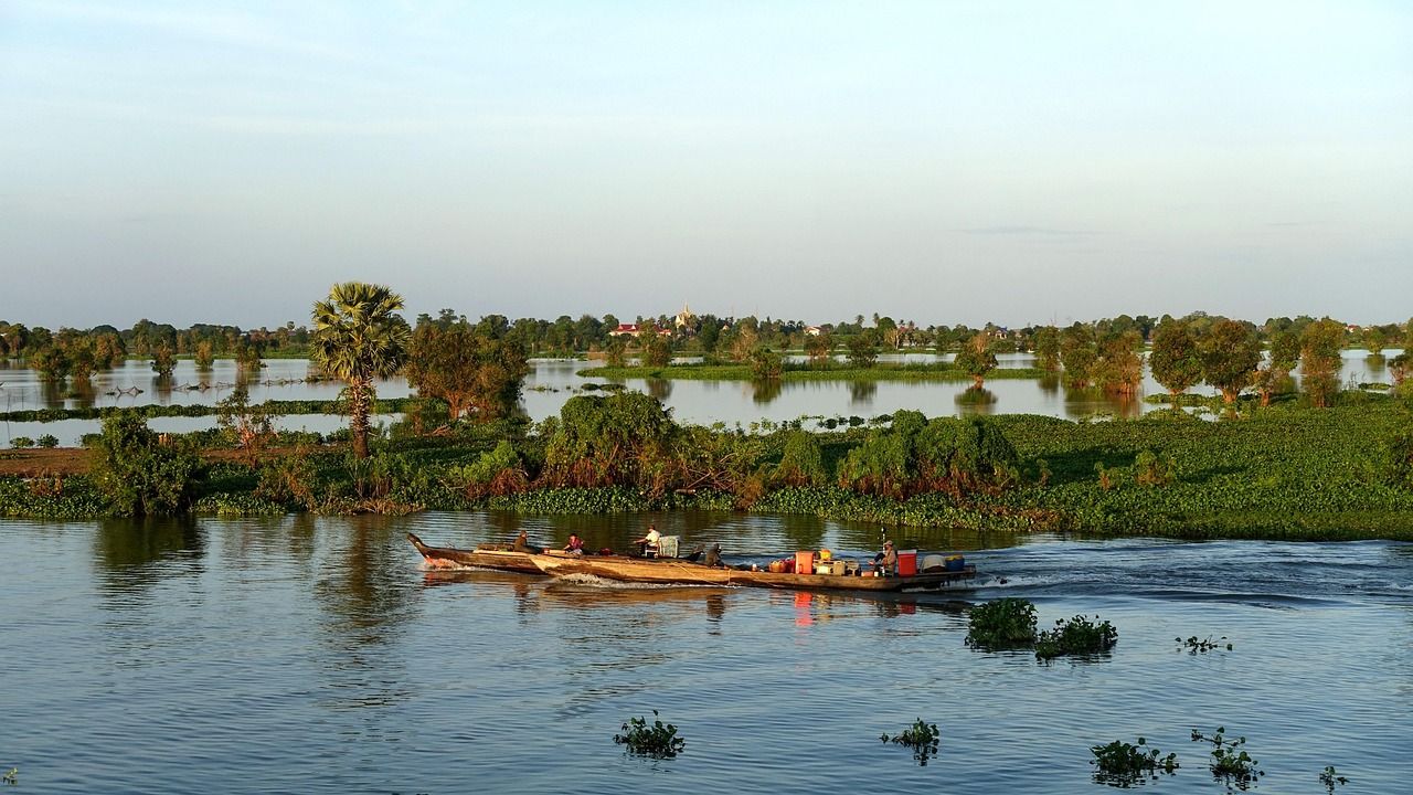 A small boat on the calm, flooded waters of the Tonle Sap near Kampong Chhnang, with trees on the horizon