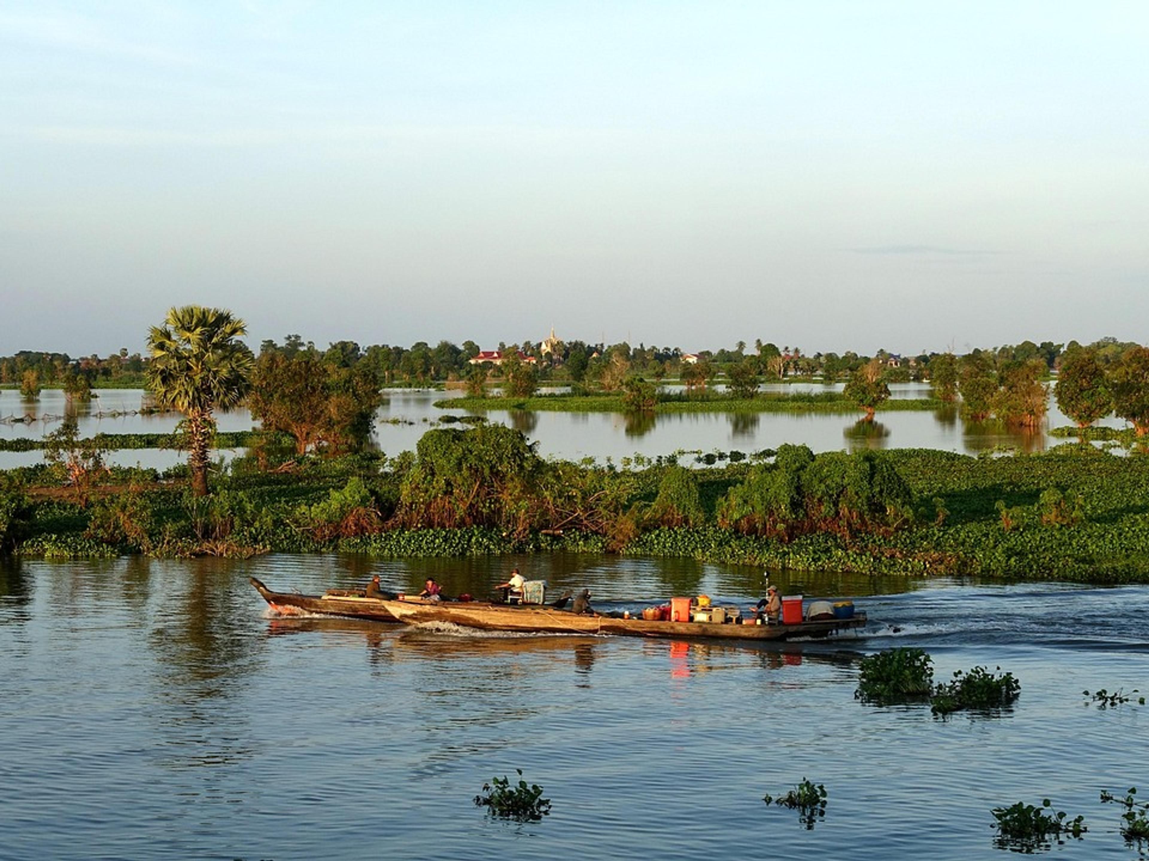 A small boat on the calm, flooded waters of the Tonle Sap near Kampong Chhnang, with trees on the horizon