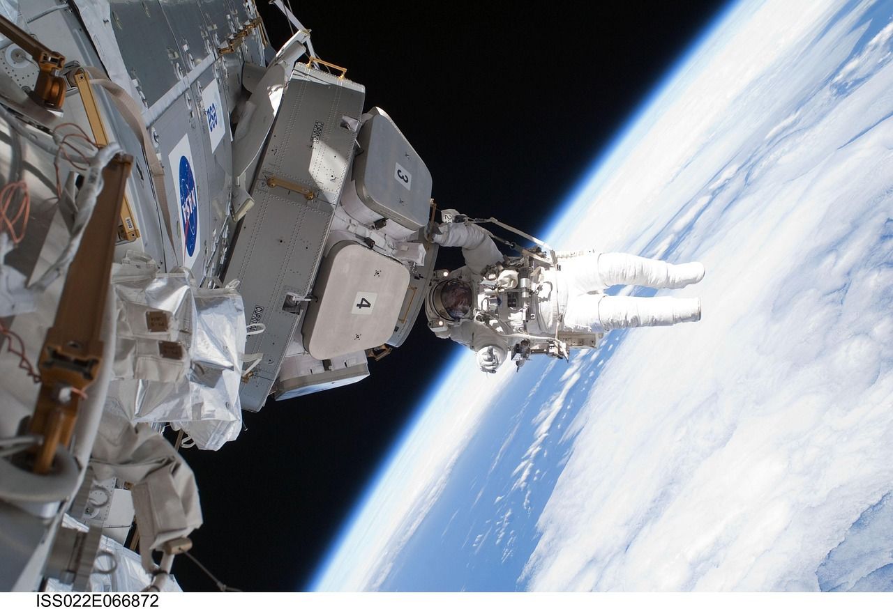 Archive NASA photo of an astronaut on a spacewalk outside the International Space Station, with Earth's clouds below