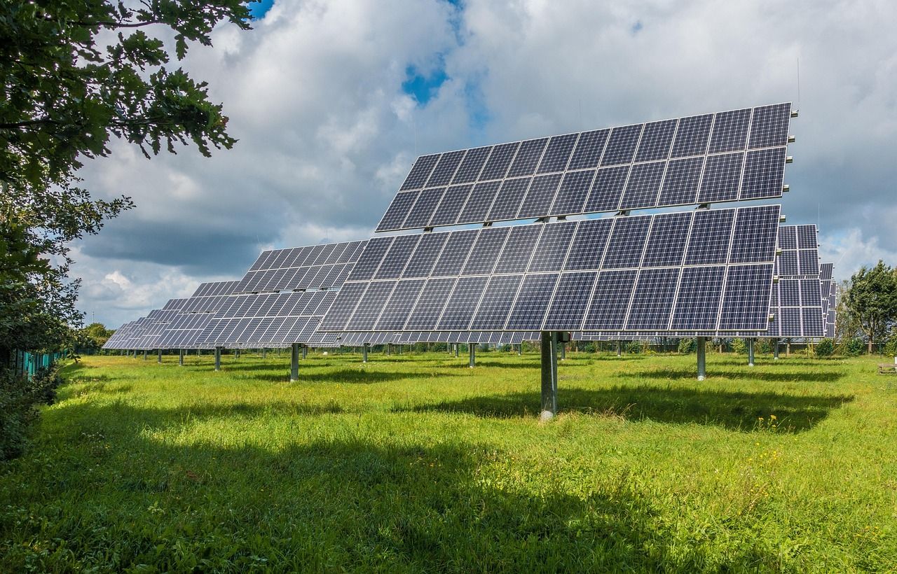 Large field of solar panels under a bright sky