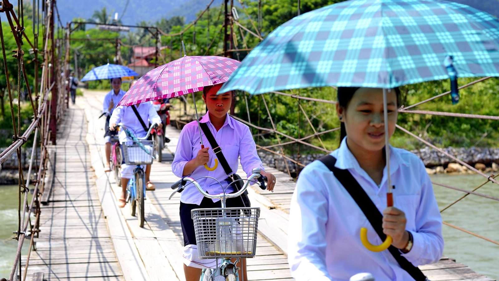 A young girl in a school uniform standing outdoors in the Lao countryside