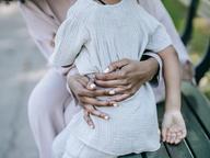 An adult tenderly embracing a child's hands outdoors, symbolizing protection and family reunion.