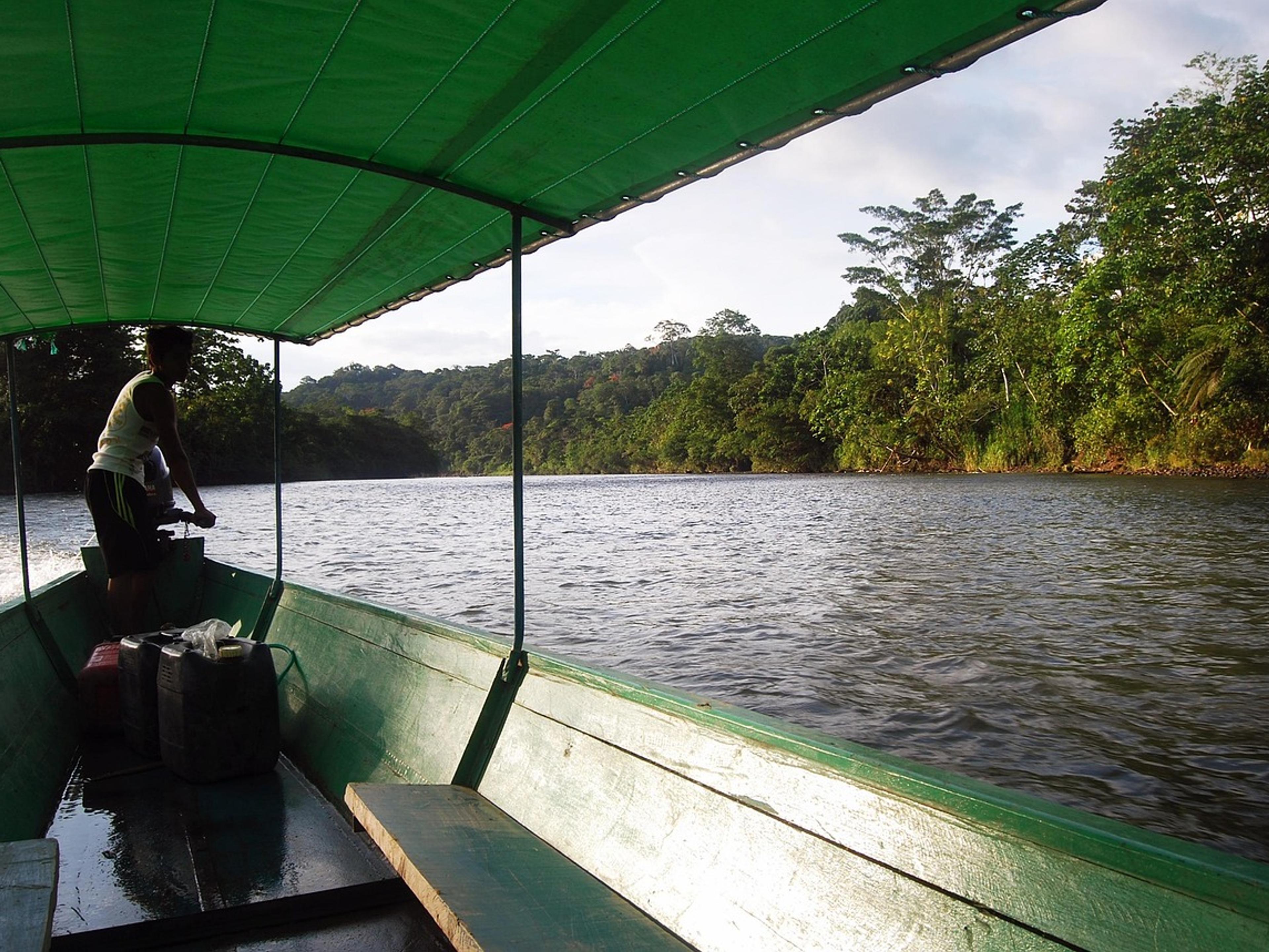 View from a covered wooden boat on a river through the Ecuadorian Amazon rainforest