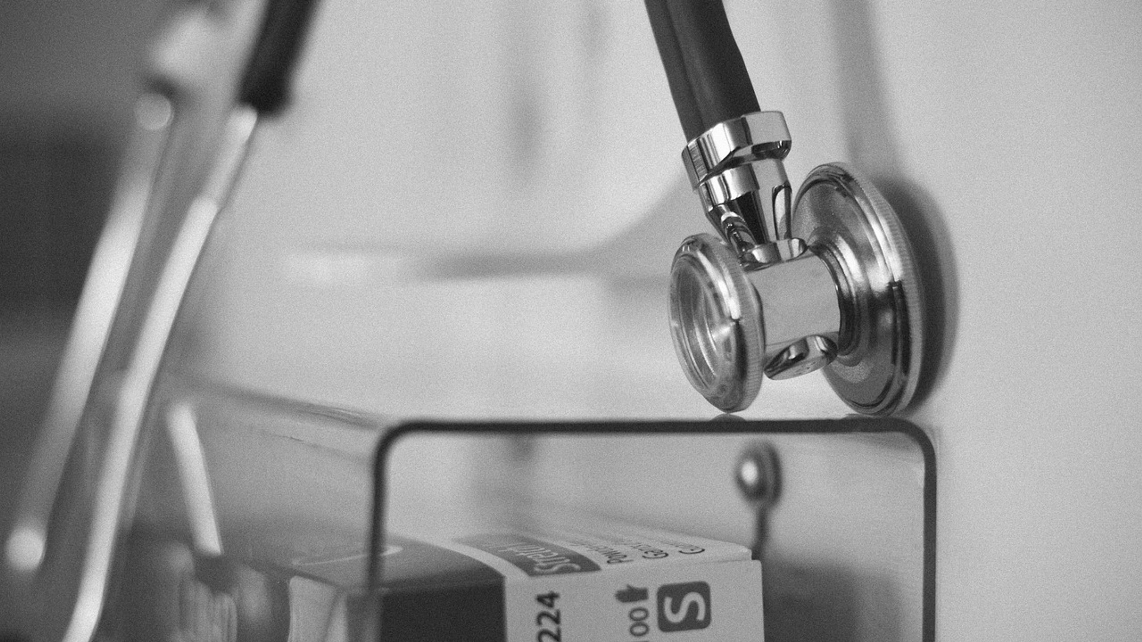Black-and-white close-up of a stethoscope hanging on a hospital rack