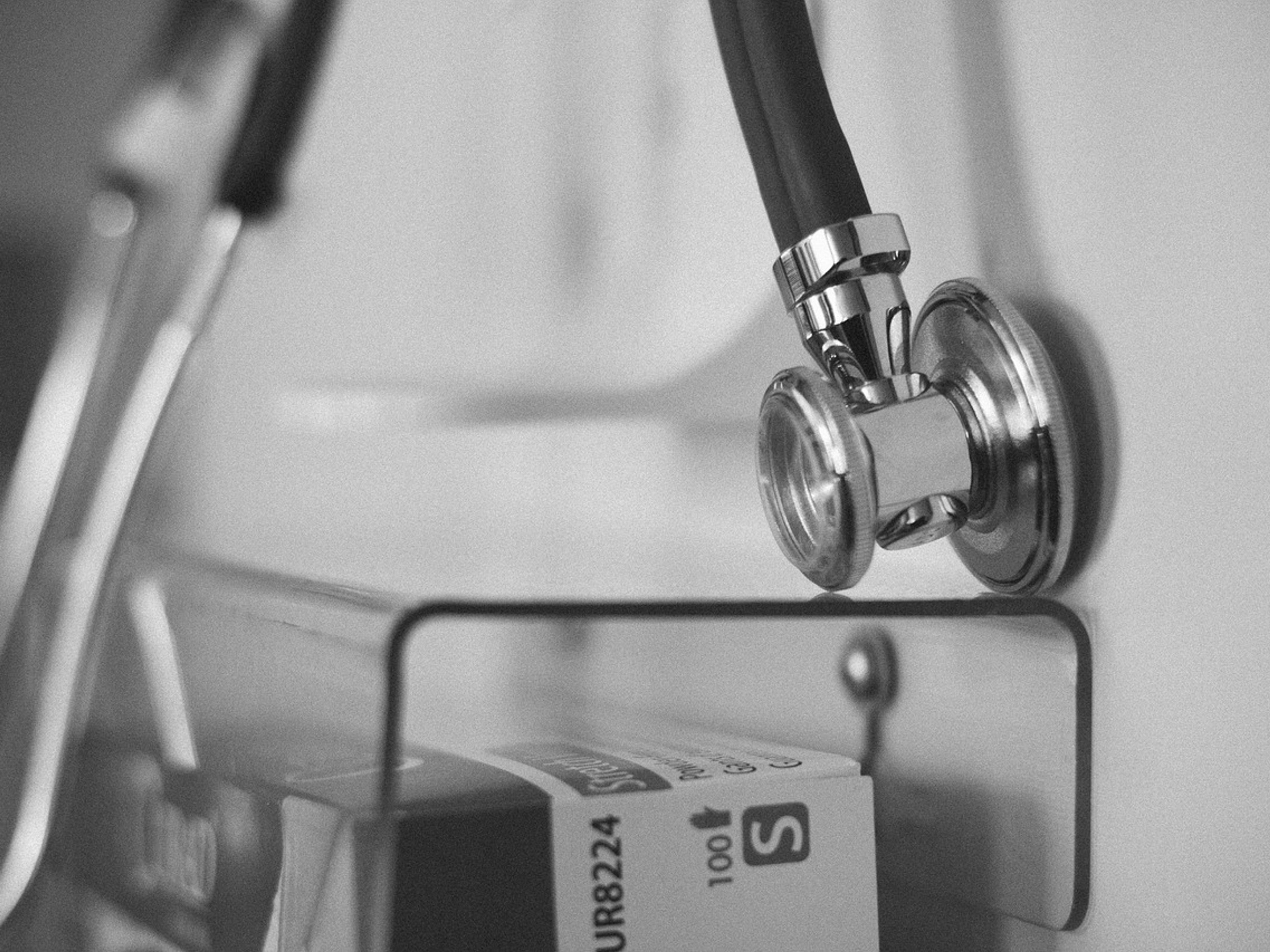 Black-and-white close-up of a stethoscope hanging on a hospital rack