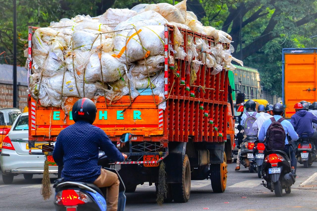 A loaded truck in busy traffic with motorbikes on a street in Bangalore, India