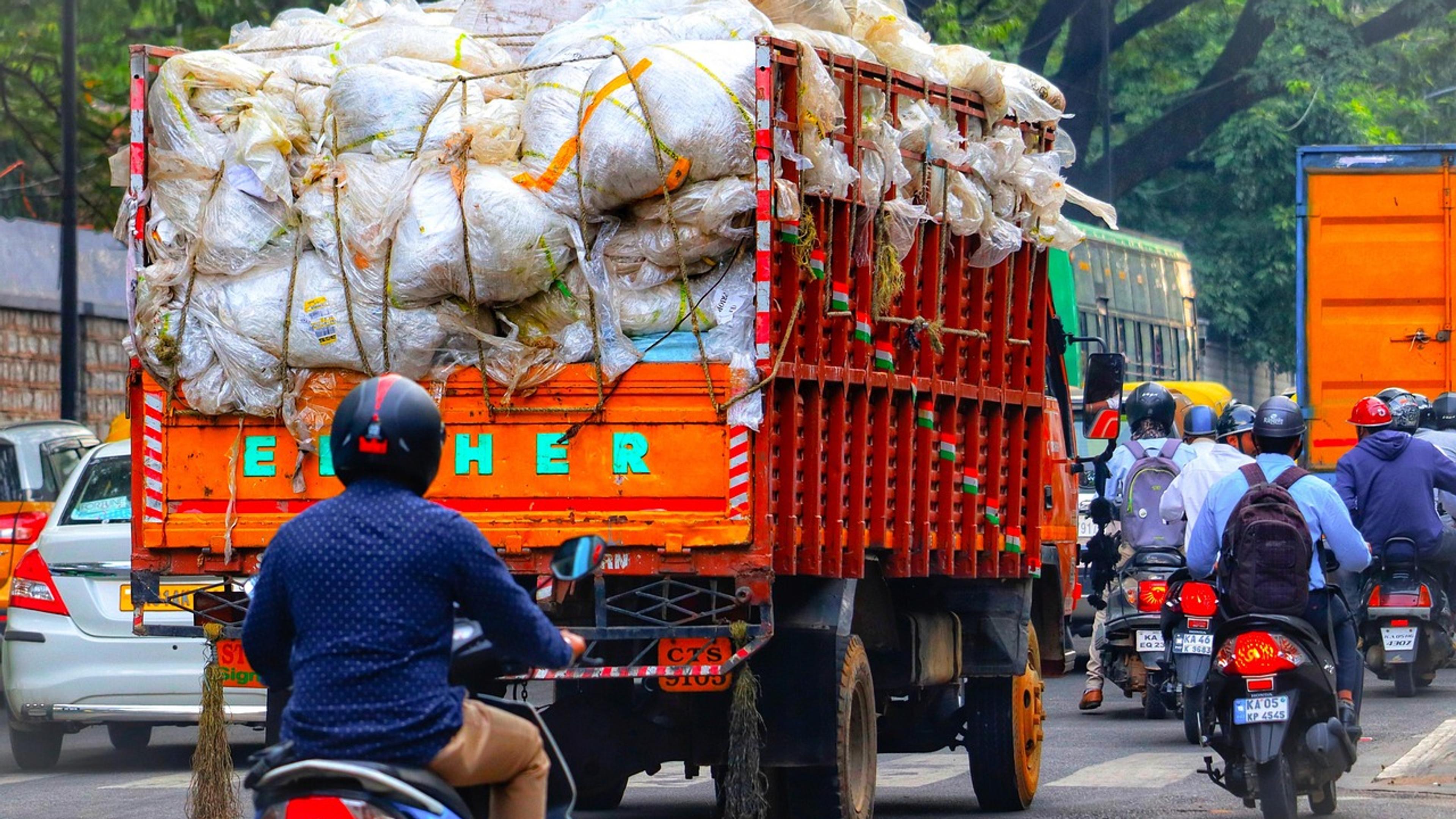 A loaded truck in busy traffic with motorbikes on a street in Bangalore, India