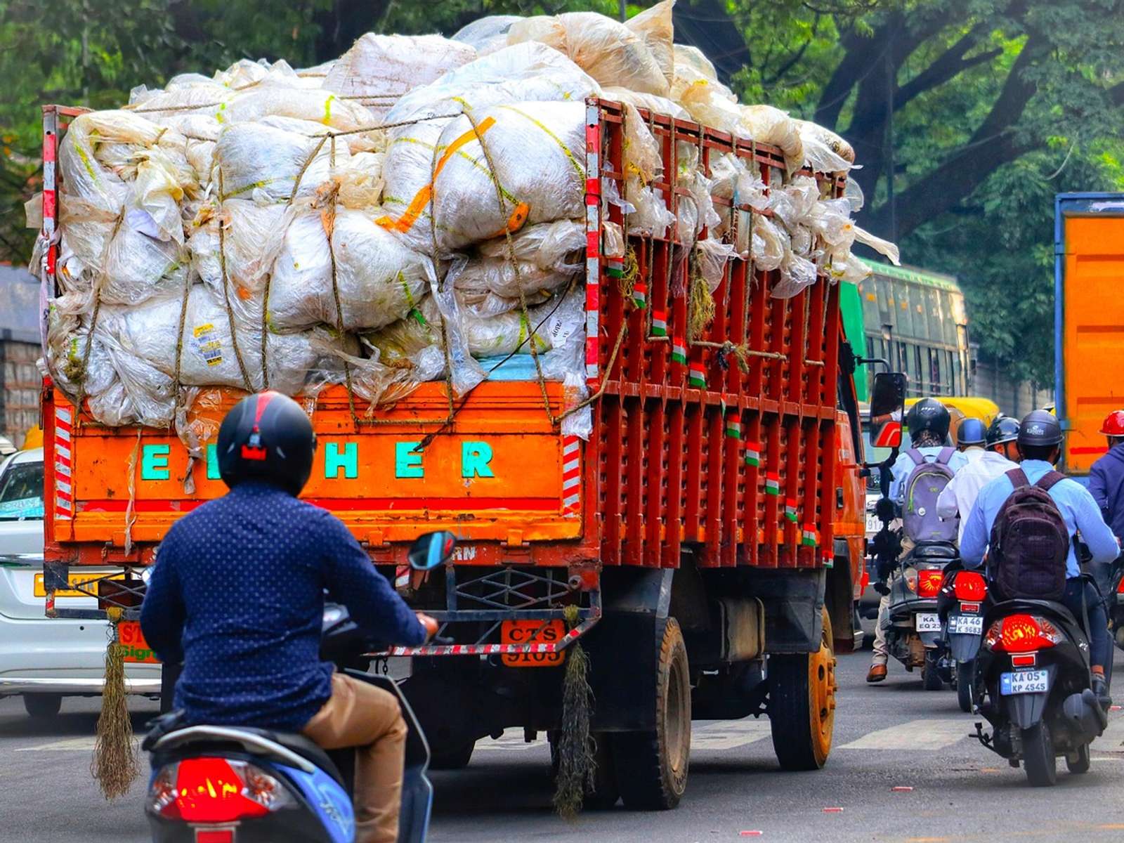 A loaded truck in busy traffic with motorbikes on a street in Bangalore, India