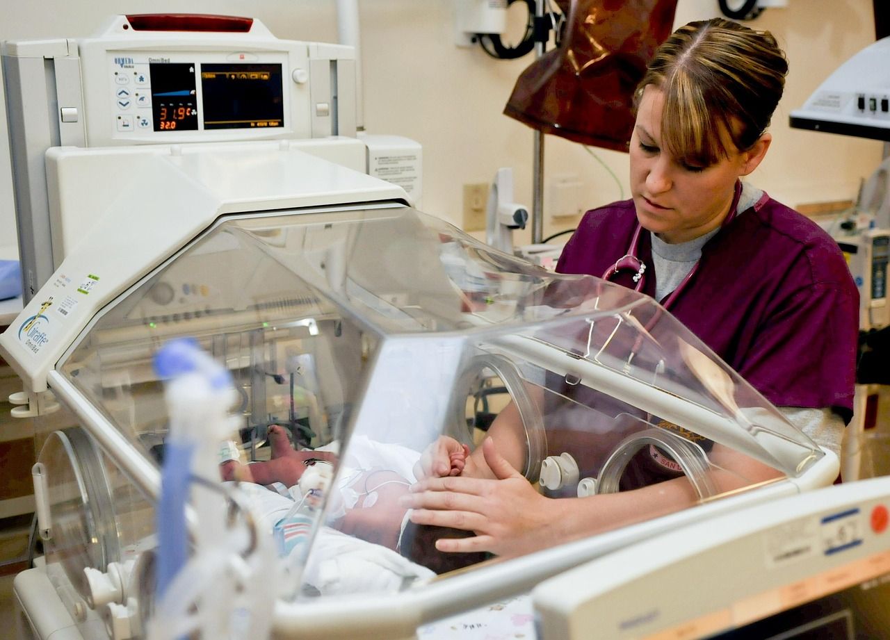 A nurse tending to a baby inside a hospital incubator