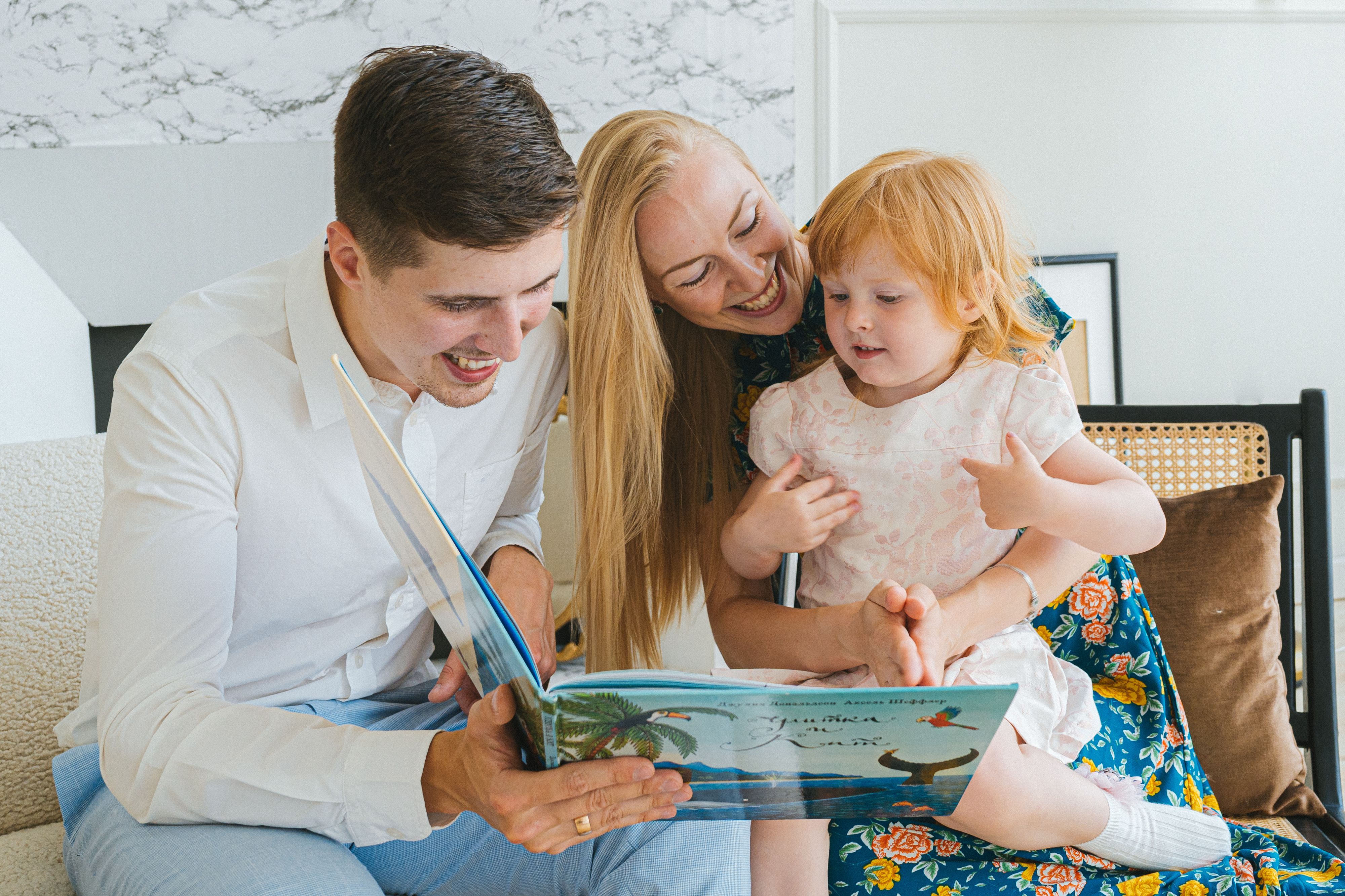 Young child reading a colorful book with a parent at home as part of an early literacy program