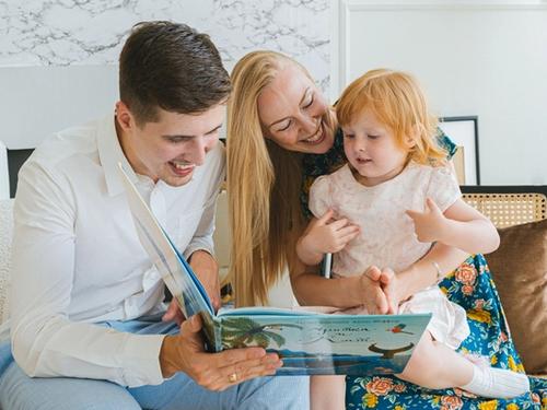 Young child reading a colorful book with a parent at home as part of an early literacy program