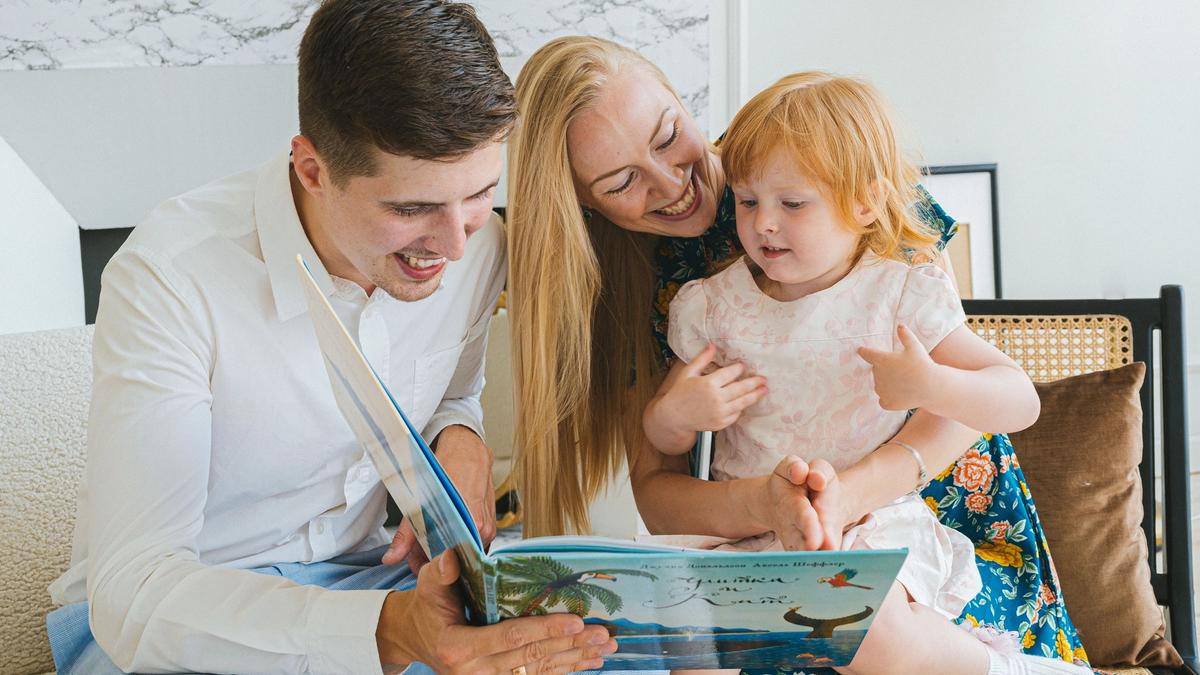 Young child reading a colorful book with a parent at home as part of an early literacy program