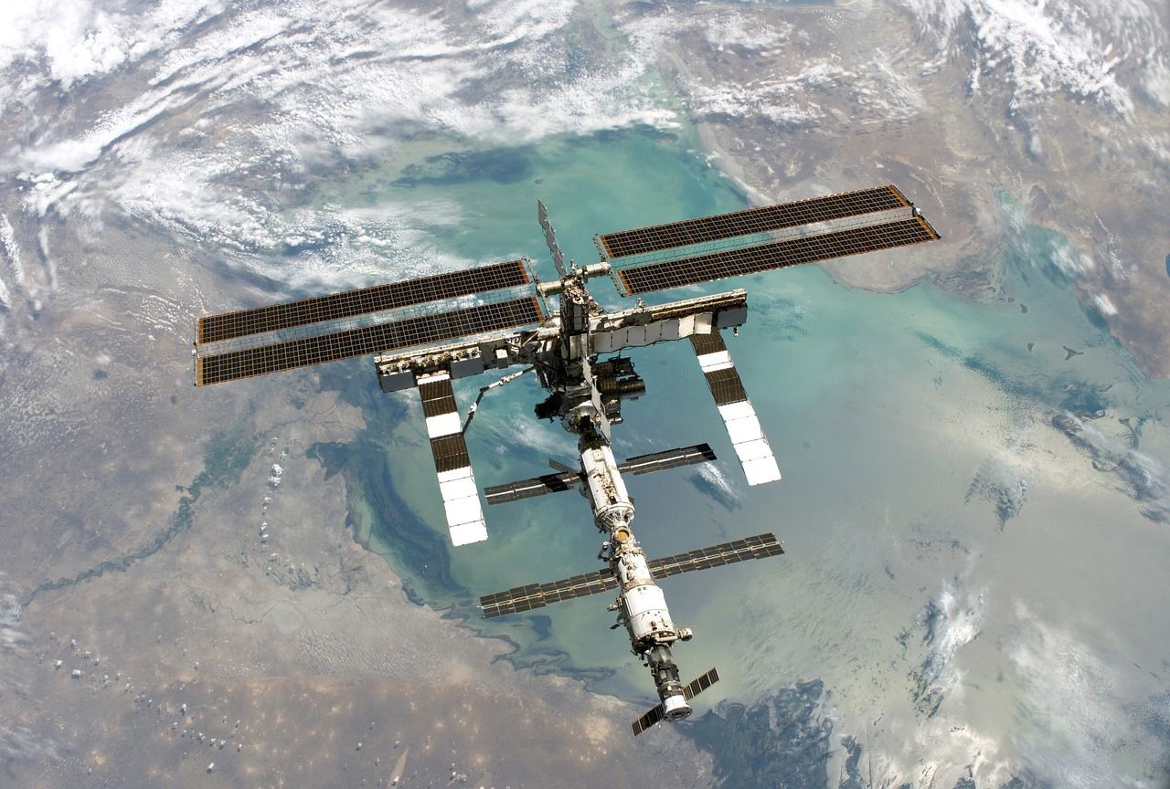The International Space Station with its solar arrays extended, seen from above against the Earth