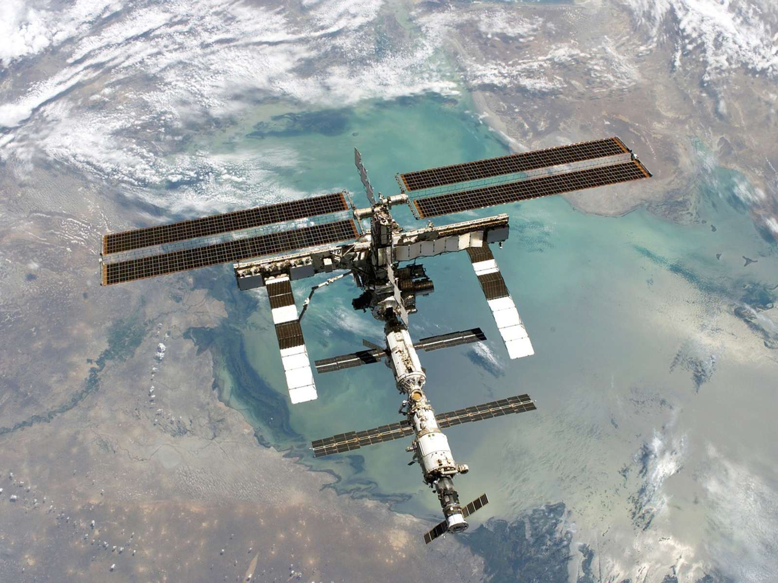 The International Space Station with its solar arrays extended, seen from above against the Earth