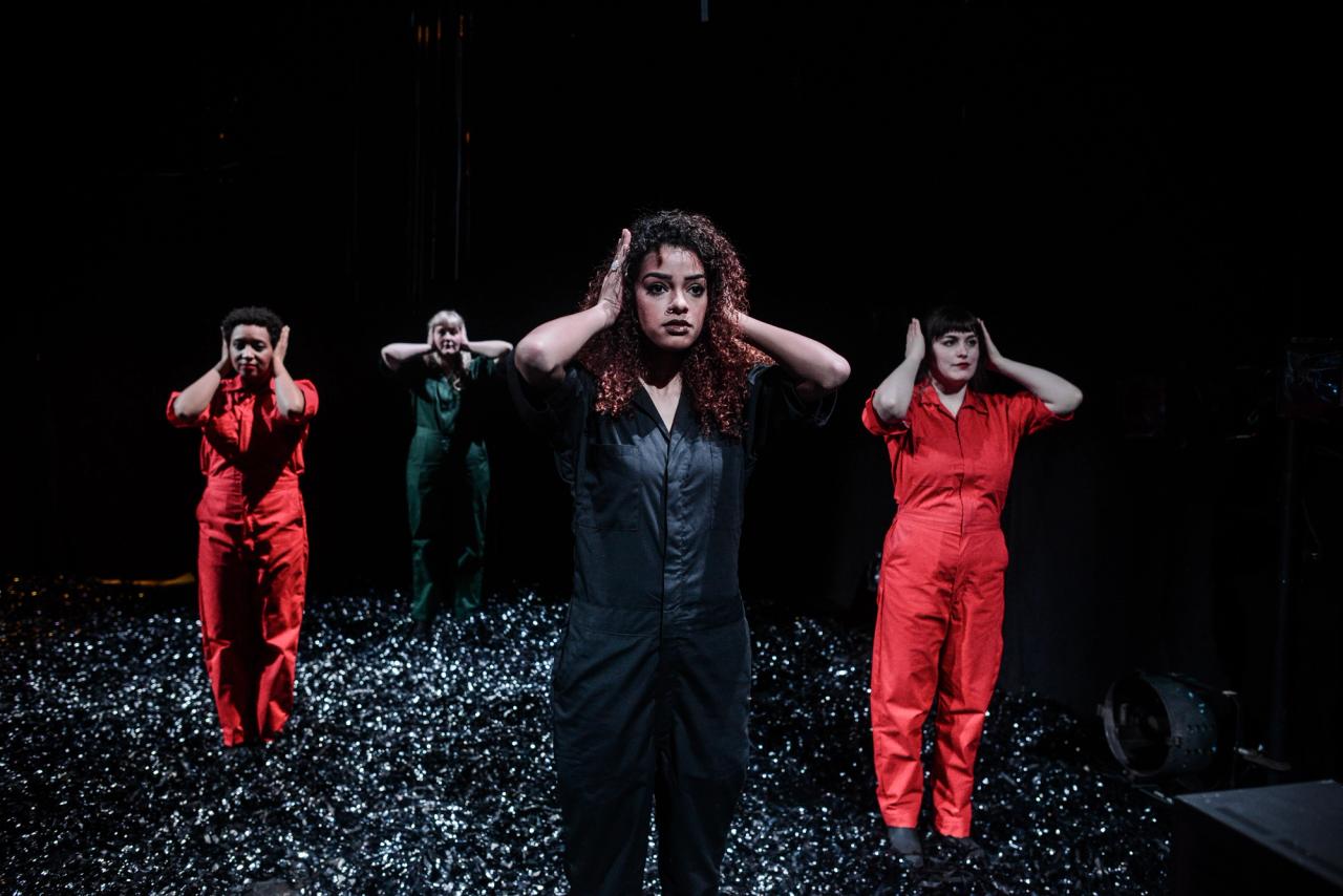 Four women hold their hands over their ears.