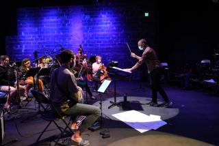 The orchestra conductor raises his baton.