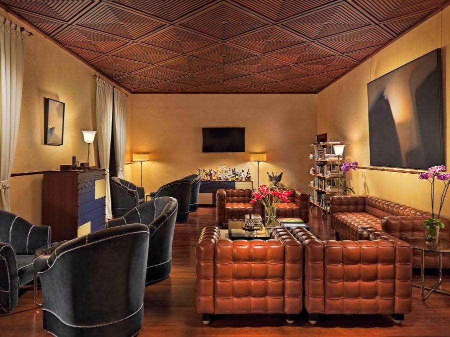 Salón del Hotel San Roque con techo de madera artesonado, sofás de cuero, butacas y obras de arte contemporáneo en las paredes.