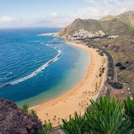 Vista de la Playa de las Teresitas, en el noreste de Tenerife, con su arena dorada, las palmeras y el pueblo de San Andrés al fondo.