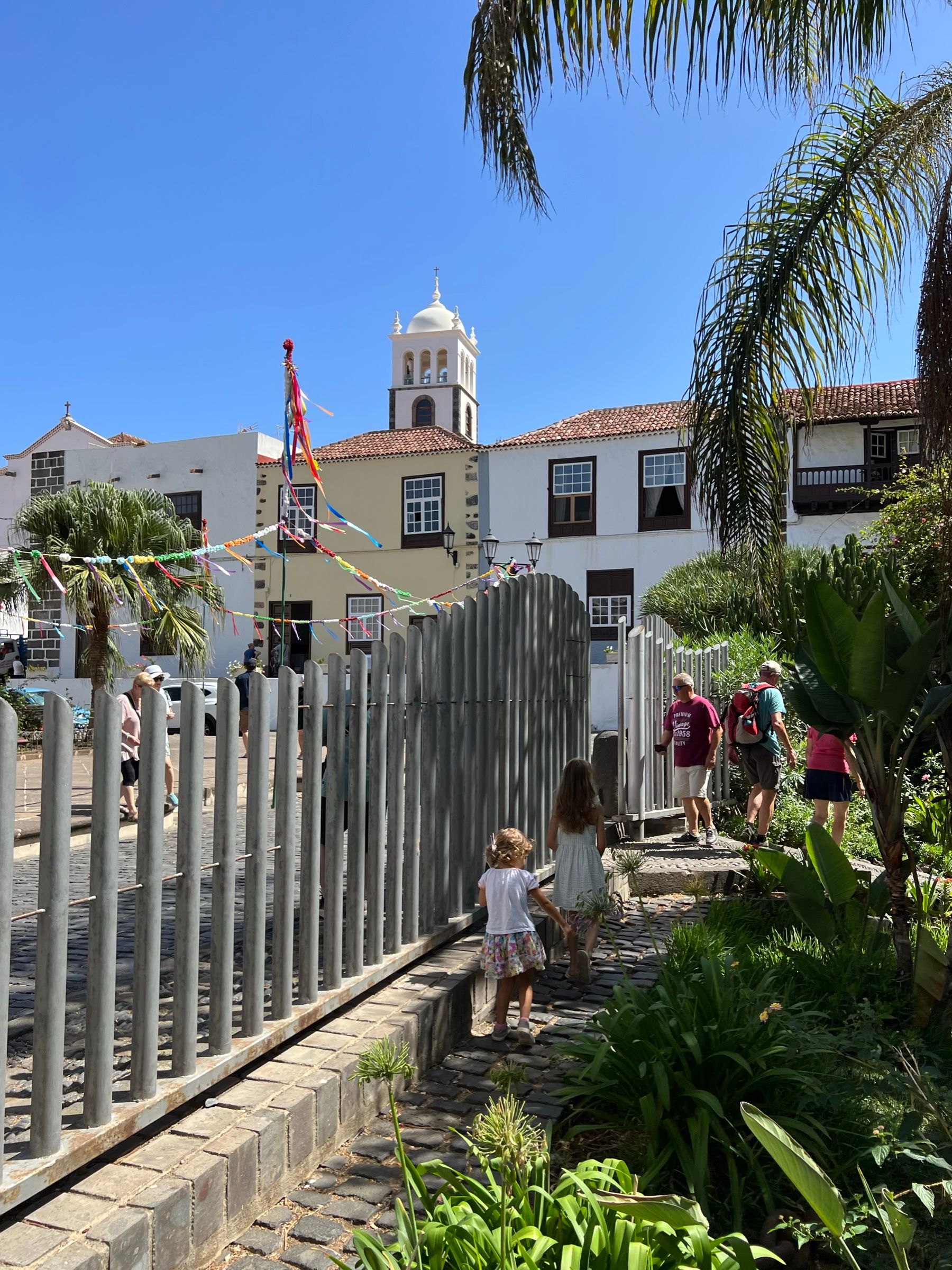 La Plaza de la Libertad de Garachico con banderitas de fiesta y la torre blanca de la iglesia de Santa Ana al fondo.