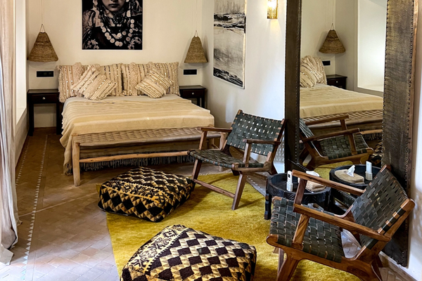 Habitación del Riad Dar Ben Slimane en Marrakech, con techo de madera, lámpara de araña y alfombra amarilla con pufs bereberes. Gábor, sentado en un sillón junto al espejo.