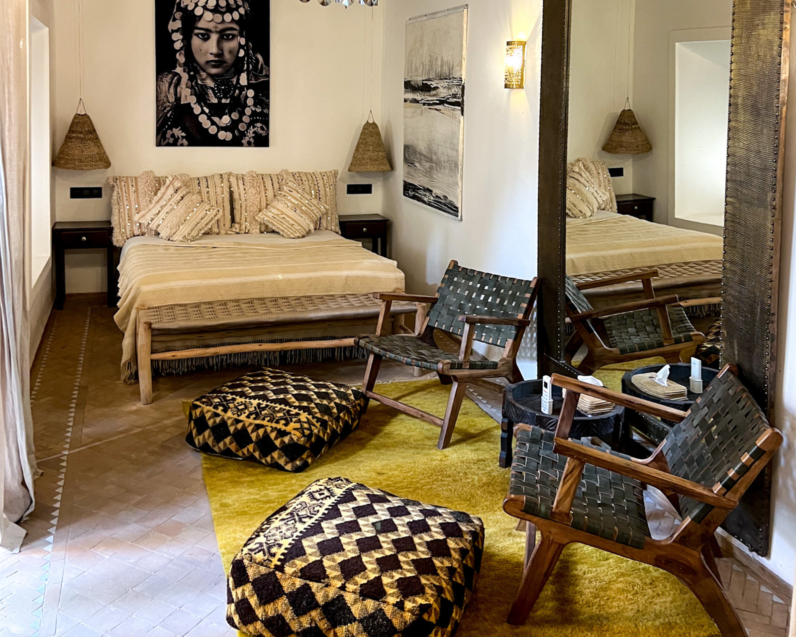 Habitación del Riad Dar Ben Slimane en Marrakech, con techo de madera, lámpara de araña y alfombra amarilla con pufs bereberes. Gábor, sentado en un sillón junto al espejo.