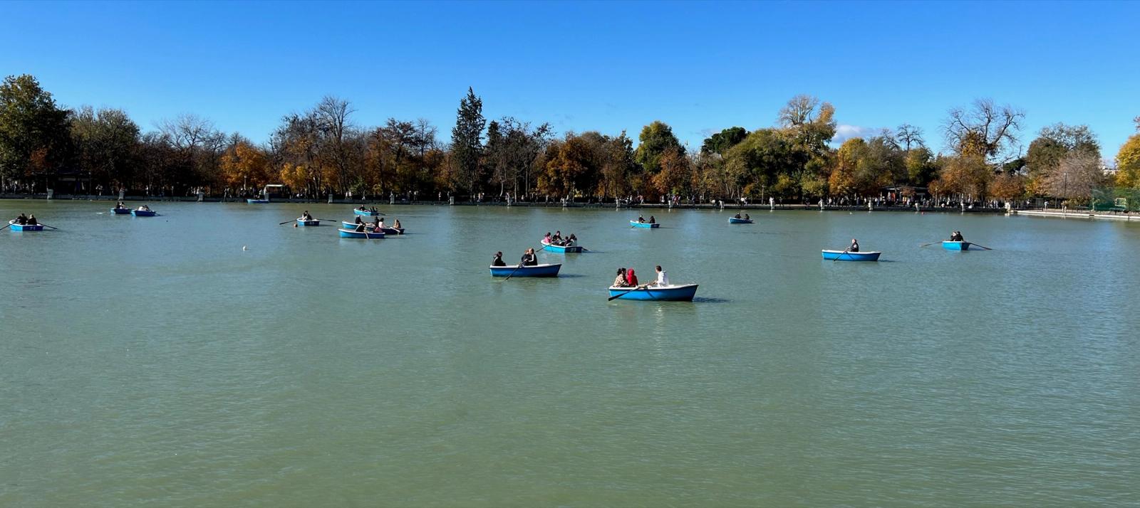 Barcas azules de remo en el Estanque Grande del Retiro, con los árboles en otoño al fondo.