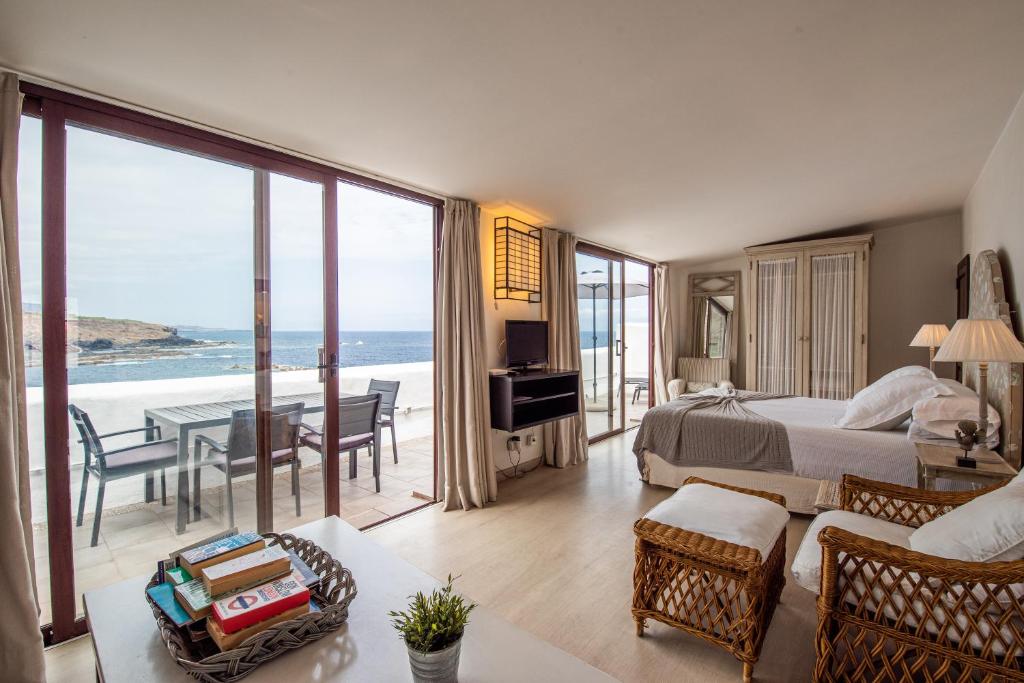 Suite de Isla Baja Suites con ventanales al Atlántico, terraza con mesa y sillas, y la cama al fondo.