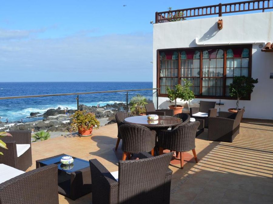 Terraza del Gara Hotel en Garachico, con sillones de mimbre y mesas frente al mar y las rocas de El Caletón.