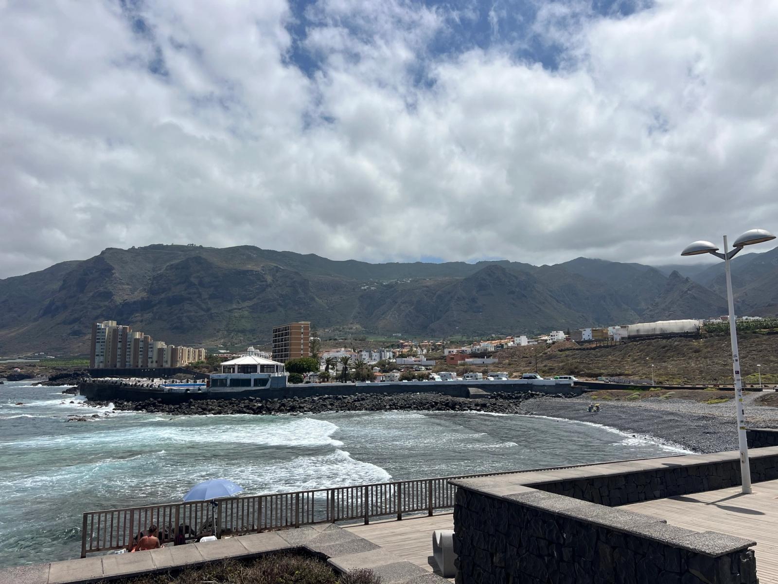 Playa de Sibora, en Los Silos: una pequeña playa de arena negra y callaos junto al Charco de los Chochos, con el pueblo y las montañas de la Isla Baja al fondo.