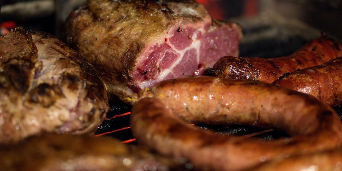 a close up of meat and sausages cooking on a grill