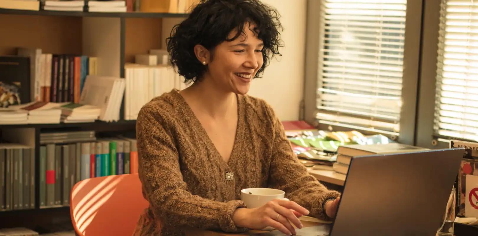 Una mujer está sentada en un escritorio usando una computadora portátil.