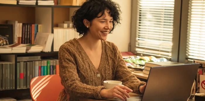 Une femme est assise à un bureau en utilisant un ordinateur portable.