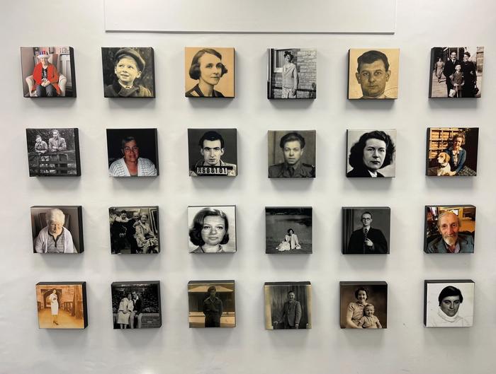 a wall filled with lots of black and white photos of people .