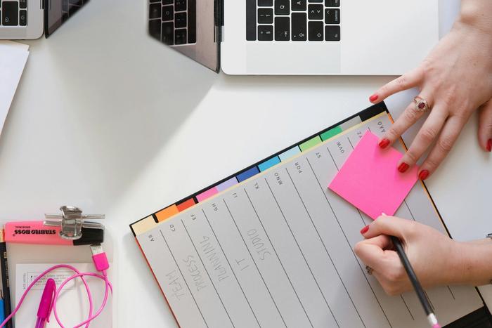 a woman is writing on a clipboard with sticky notes and a pencil .