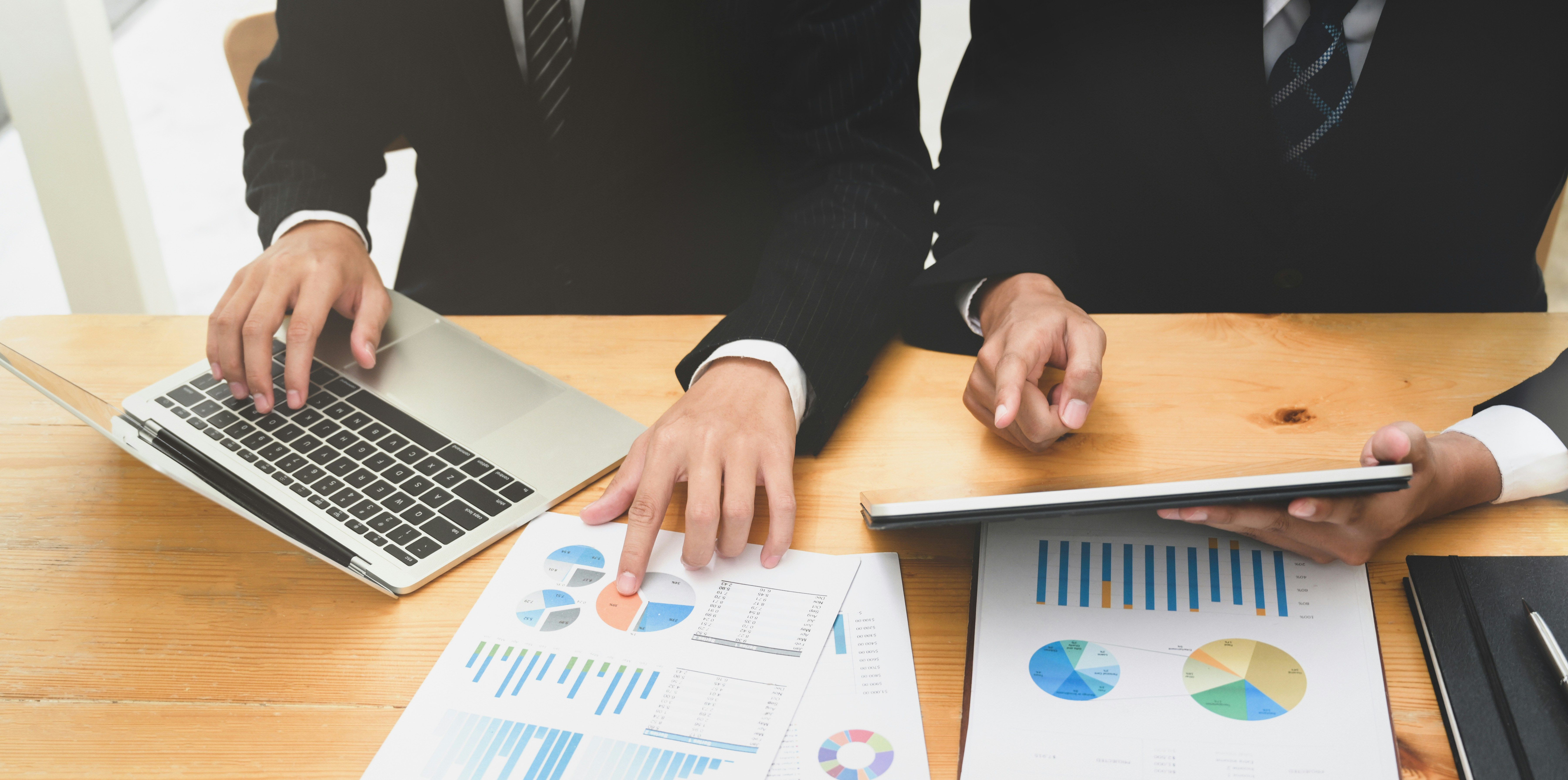 a group of business people are sitting at a table looking at charts and graphs .