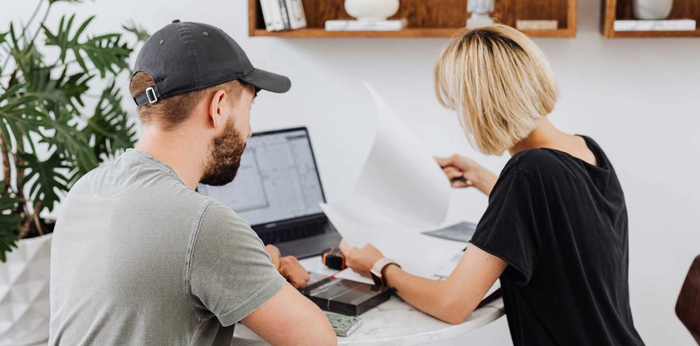 Two people in front of a laptop looking at documents