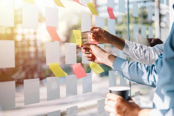 a group of people are putting sticky notes on a glass wall .