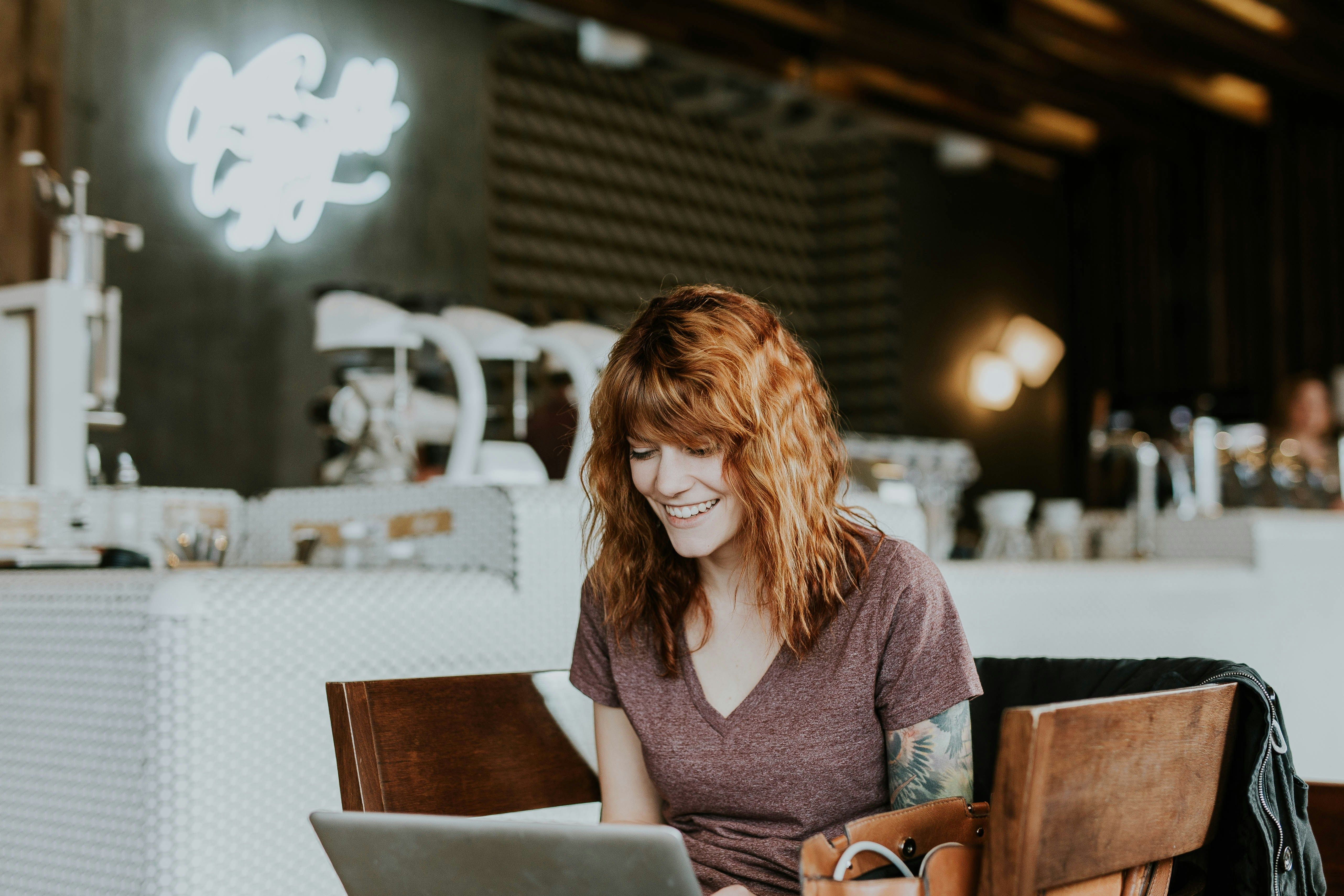 a woman is sitting at a table in a cafe using a laptop computer .