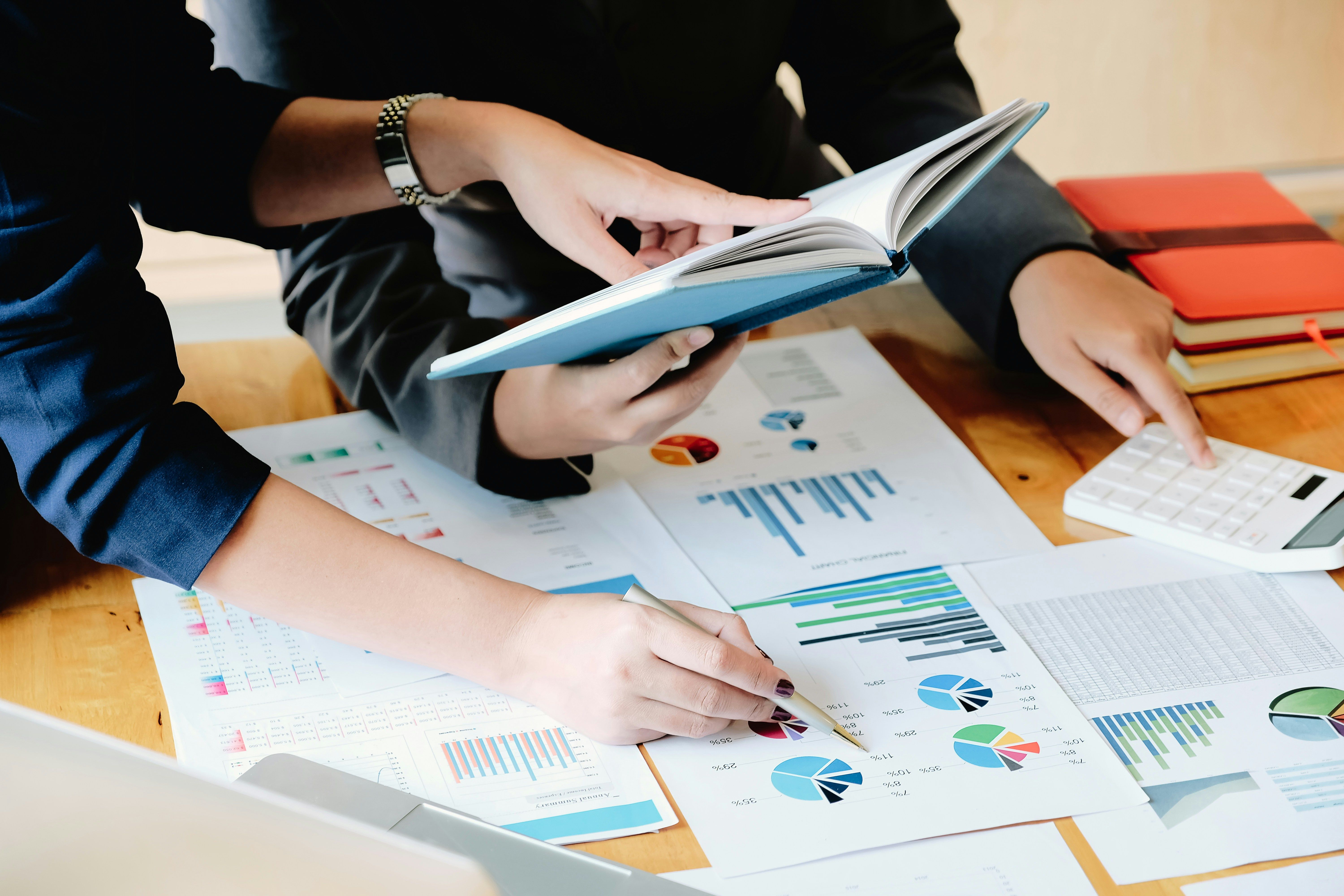 a group of people are sitting at a table looking at charts and graphs .