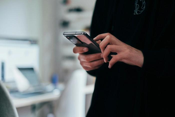 a person is holding a cell phone in their hands .