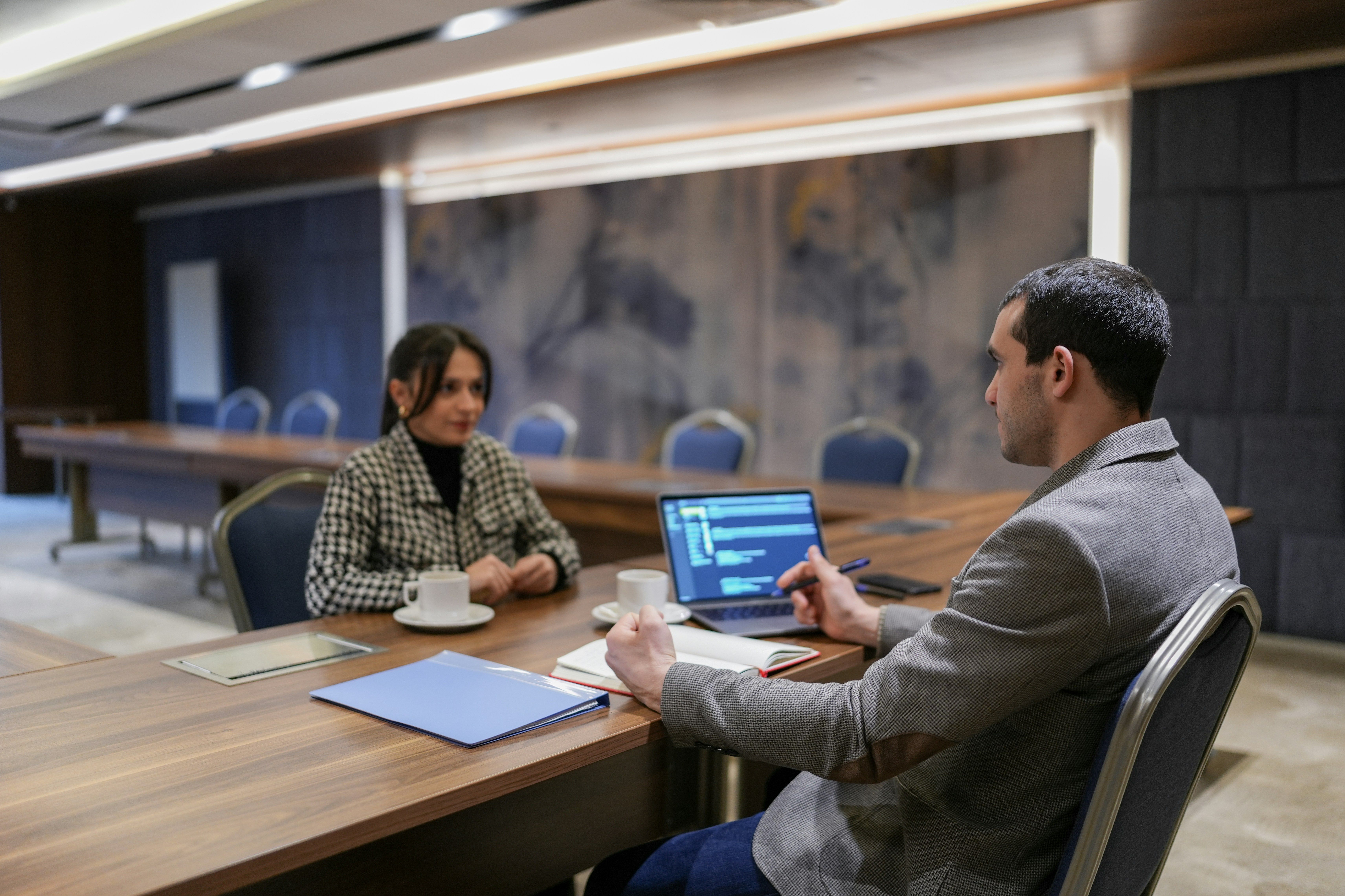 a man and a woman are sitting at a table with a laptop .