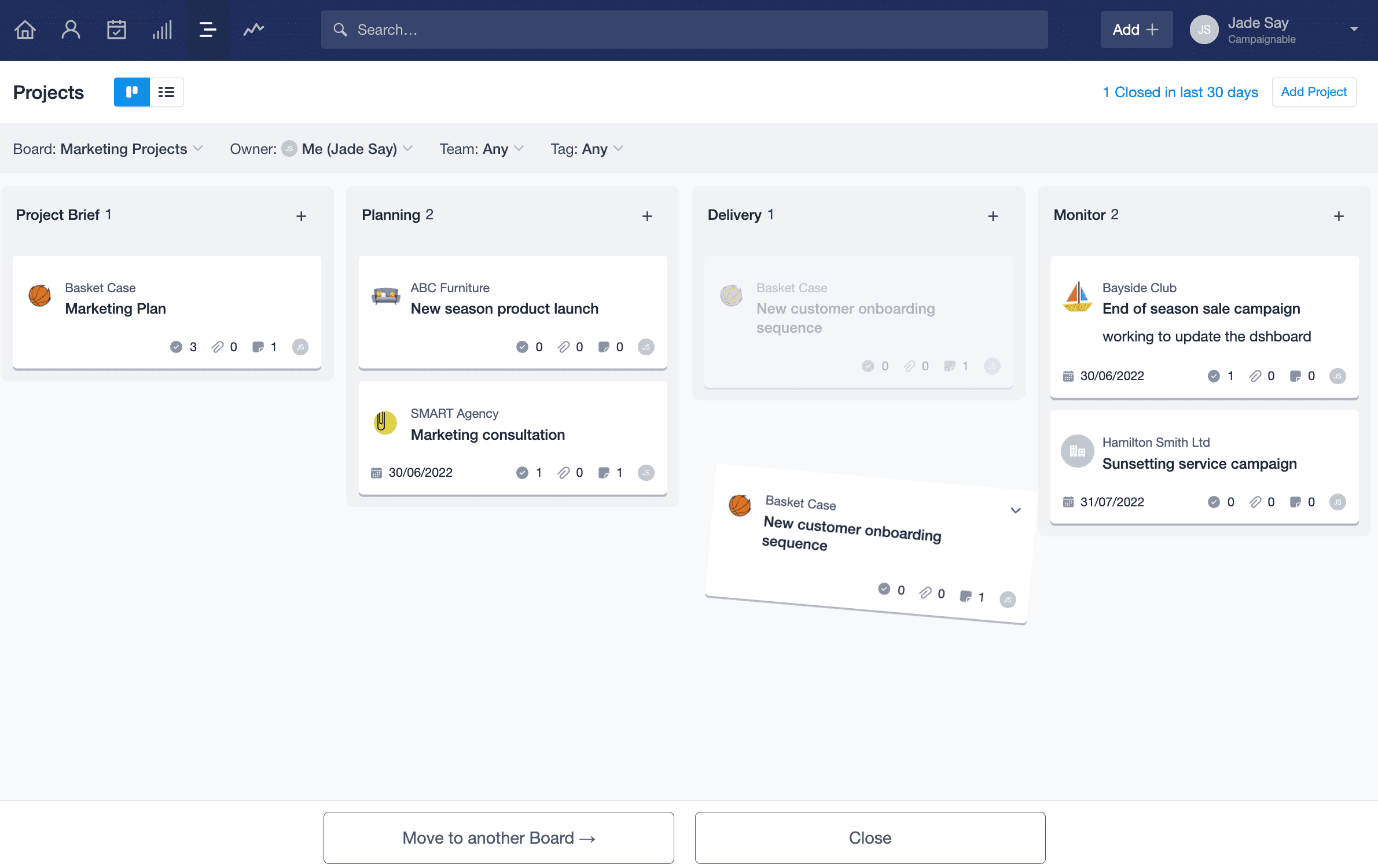 La vista de kanban del proyecto se muestra con una tarjeta de Proyecto siendo arrastrada hacia la parte inferior de la página. Aparecen dos botones con la opción de cerrar el proyecto o moverlo a otro tablero